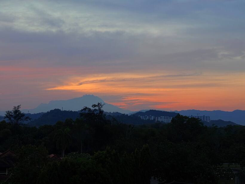 Layers of hills and haze at dusk with a single cloud lit from below