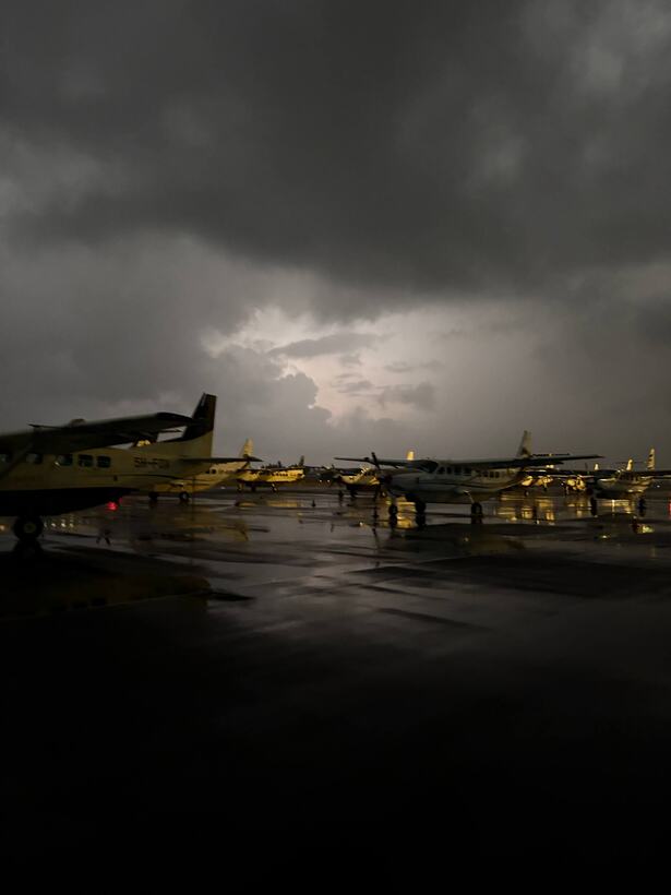 Light aircraft parked on a wet apron at dusk under a heavy storm sky